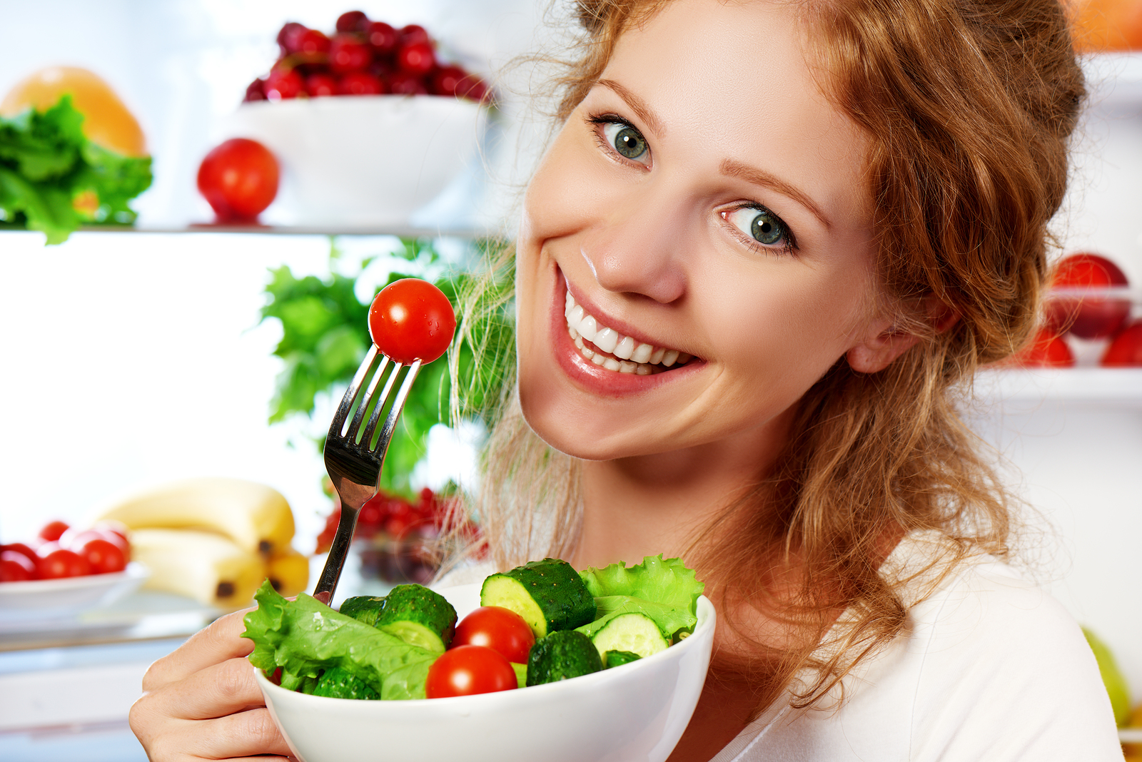 happy woman eats healthy food vegetable vegetarian salad about refrigerator