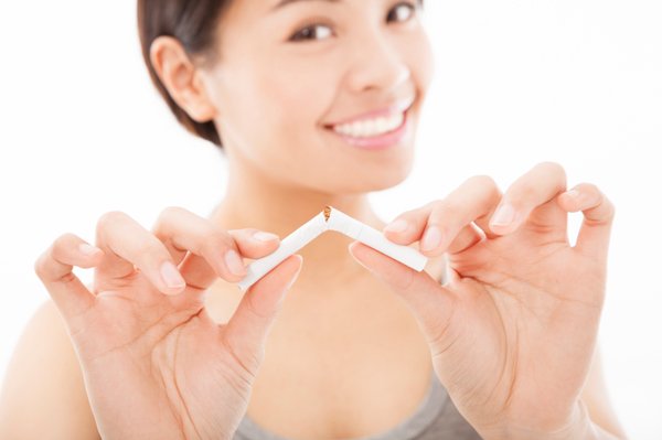 smiling woman breaking cigarette and no smoking concept