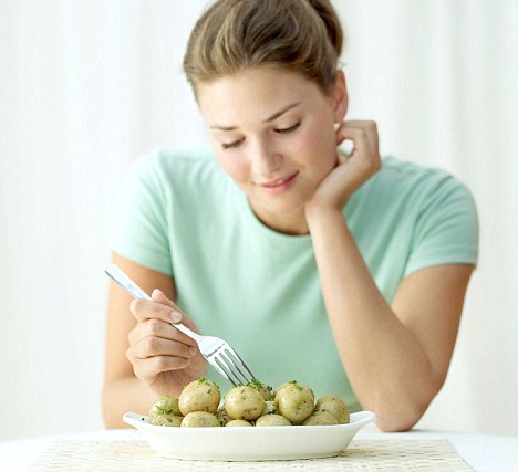 Caption Young woman holding a fork in a dish of potatoes By Stockbyte Releases Model: YES / Property: NO